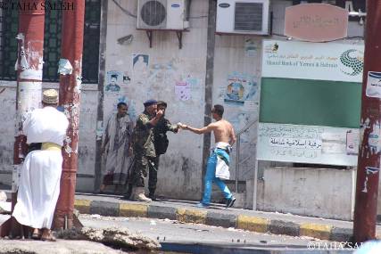 صورة لمتظاهر يمد جندي بالبصل ليسعف نفسه من آثار الغاز في تعز